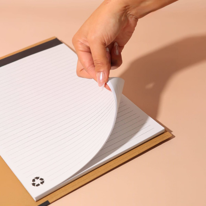 A hand flipping through lined pages of a brown A4 padfolio with a logo on the bottom corner.