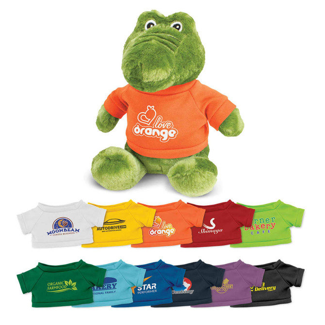 A green crocodile plush toy wearing an orange shirt, with various other colourful shirts displayed beneath it.