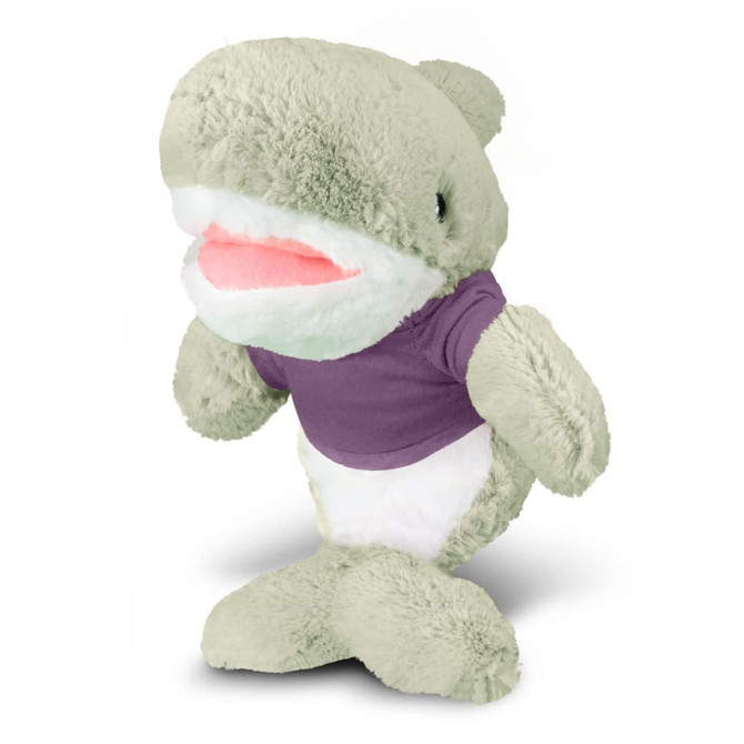 A grey plush shark toy wearing a purple T-shirt, with a white underbelly and smiling mouth. It has a logo.