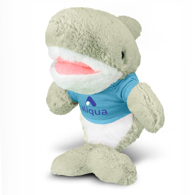 A plush shark toy in light grey, wearing a blue shirt with a logo, featuring a smiling expression.