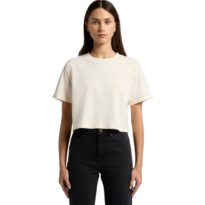 A cropped, short-sleeve t-shirt in a light cream colour, displayed on a model wearing black jeans. The shirt features a logo.