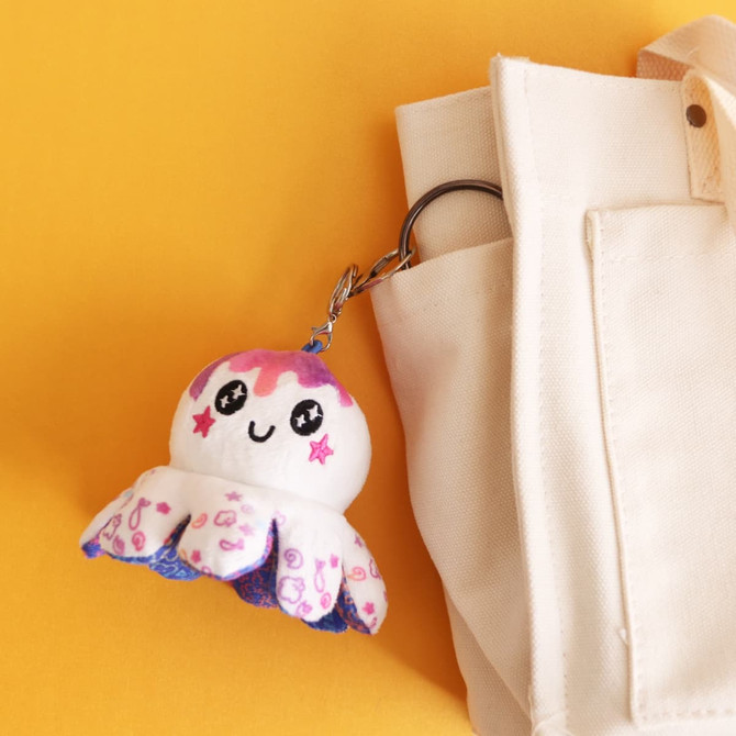 A small reversible octopus plush toy in pink and blue colours attached to a bag pocket.