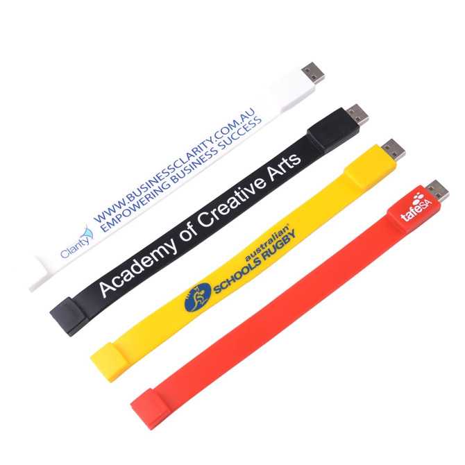 A set of four rectangular silicone wristband flash drives in white, black, yellow, and red, each with a logo.