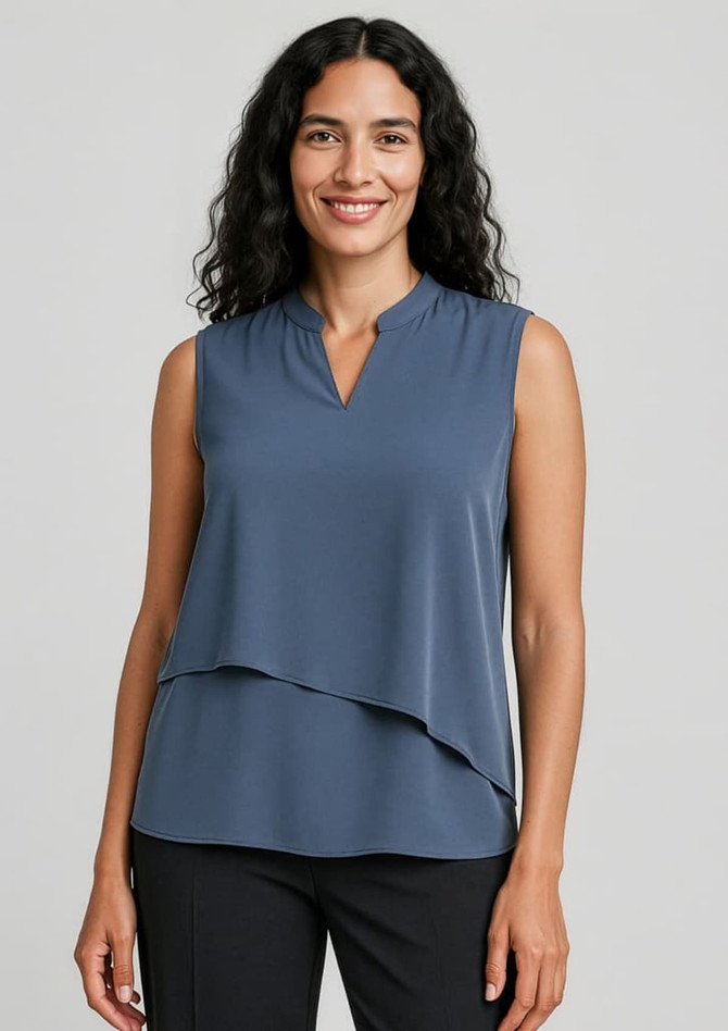 A sleeveless layered blouse in a soft blue hue, featuring a v-neckline and loose fit. The model is smiling, showcasing the top.