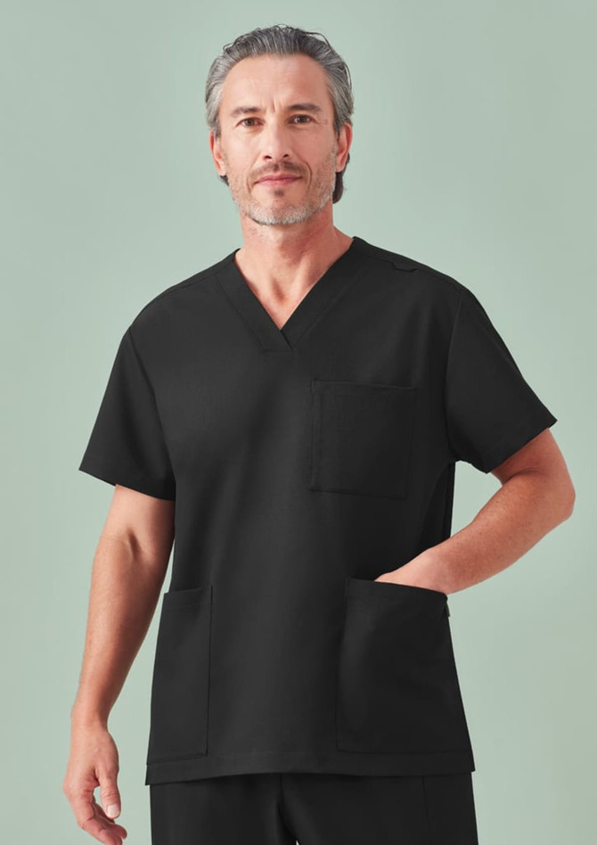 A unisex black V-neck scrub top with a pocket, featuring a model standing against a light green background.