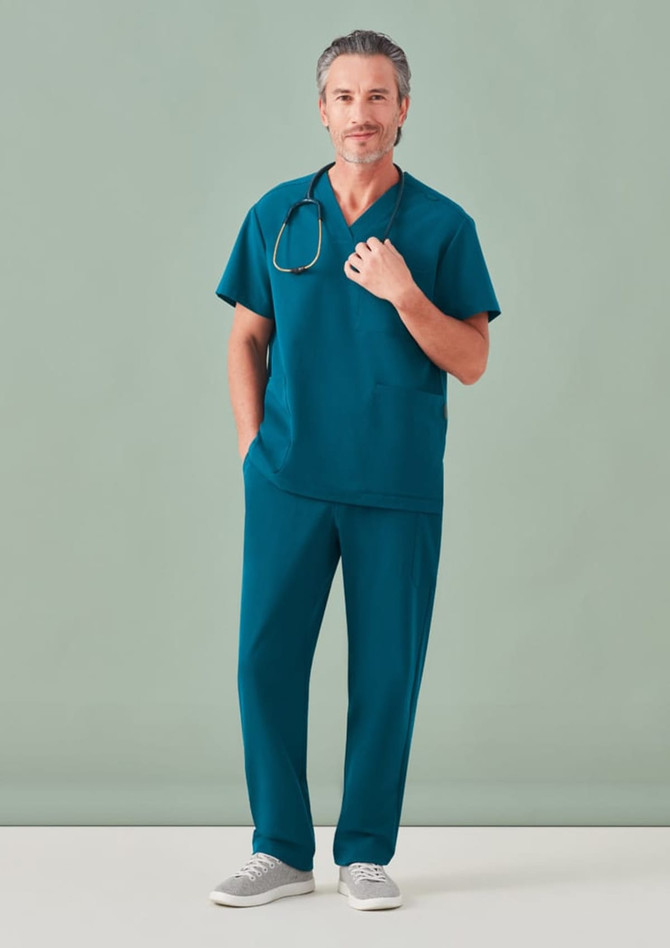 A man in teal unisex scrub pants and a matching top, wearing a stethoscope around his neck.