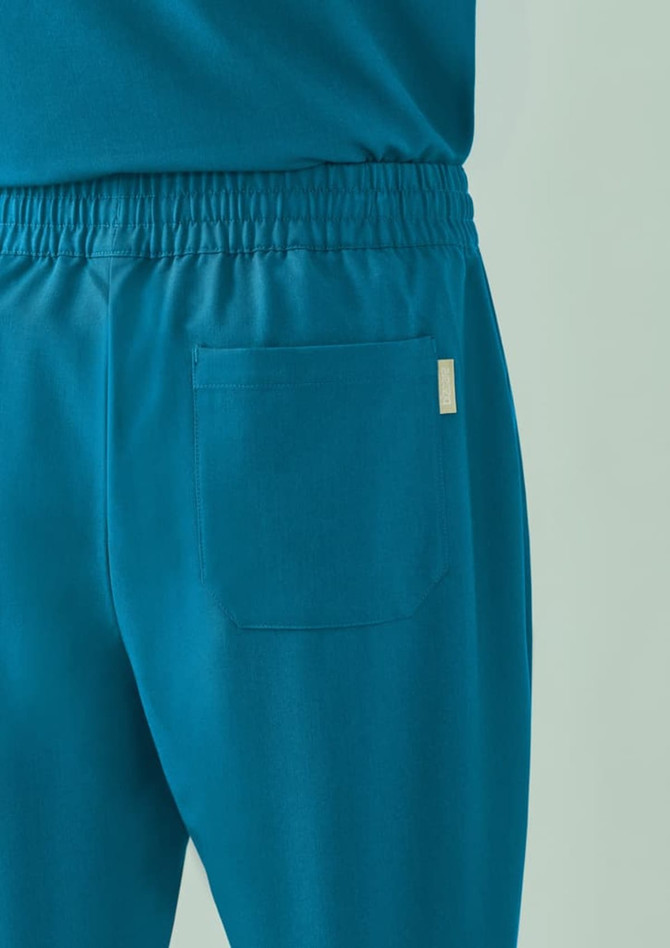 A pair of teal unisex scrub pants featuring an elastic waistband and a back pocket. Branding is visible.