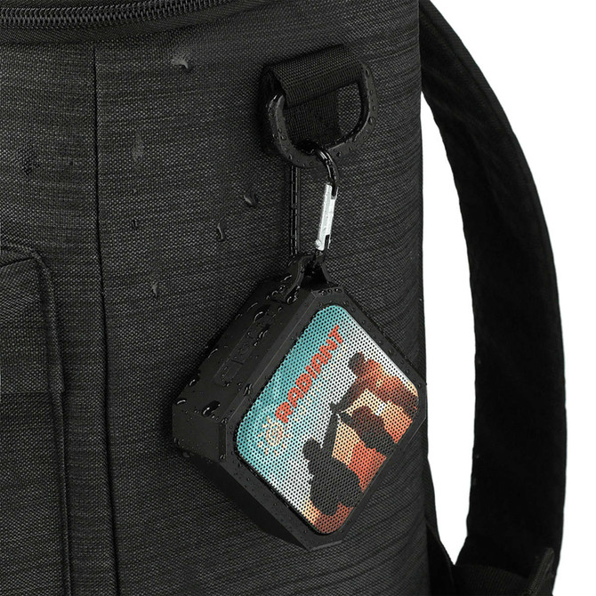 A black waterproof Bluetooth speaker with colourful designs, attached to a bag with a clip.