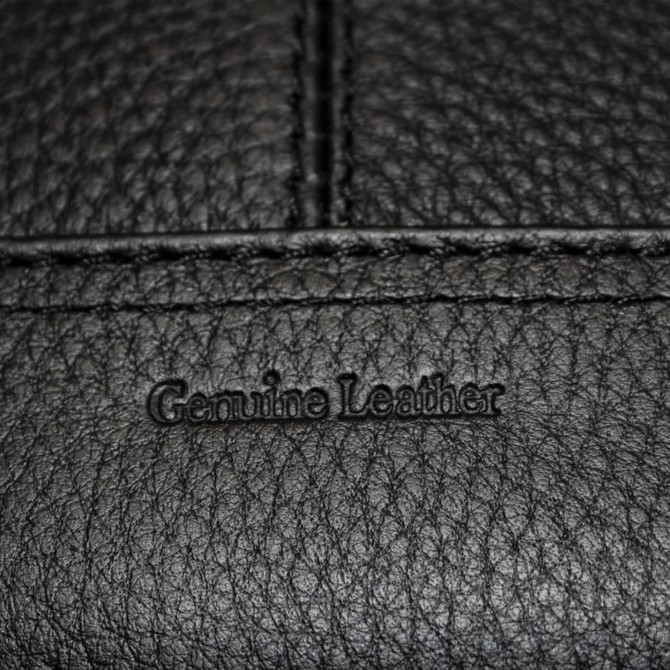 A close-up of a black genuine leather surface featuring embossed text.