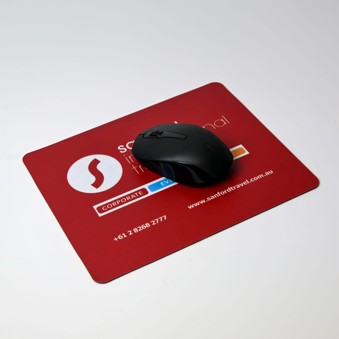 A black optical mouse on a red mouse mat featuring a logo and contact information. A black optical mouse on a red mouse mat featuring a logo and contact information.