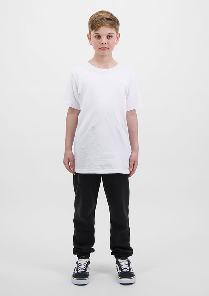 A child stands wearing a plain white t-shirt and black track pants, complemented by black and white sneakers.