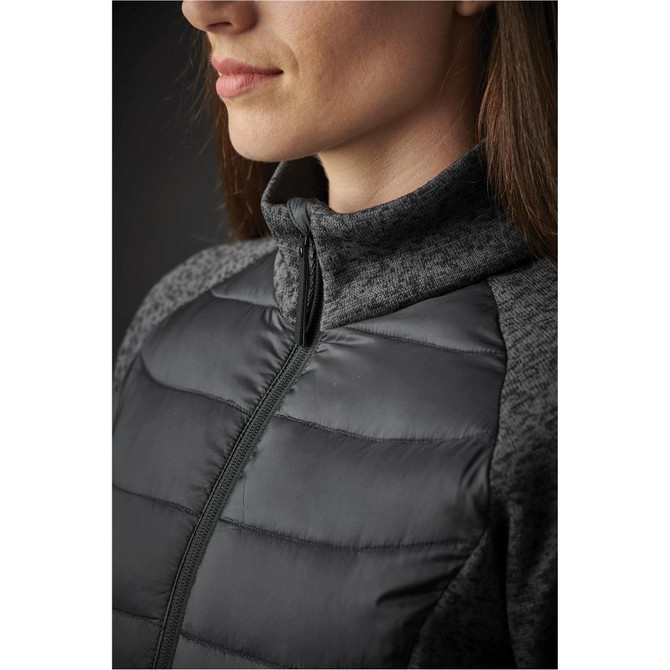A close-up of a women's jacket featuring a black quilted front and grey textured sleeves, with a zippered collar and a logo.