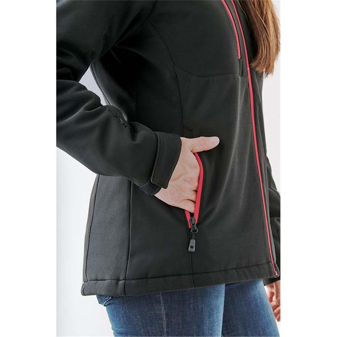 A close-up of a black women's softshell jacket featuring red accents and a zippered pocket.