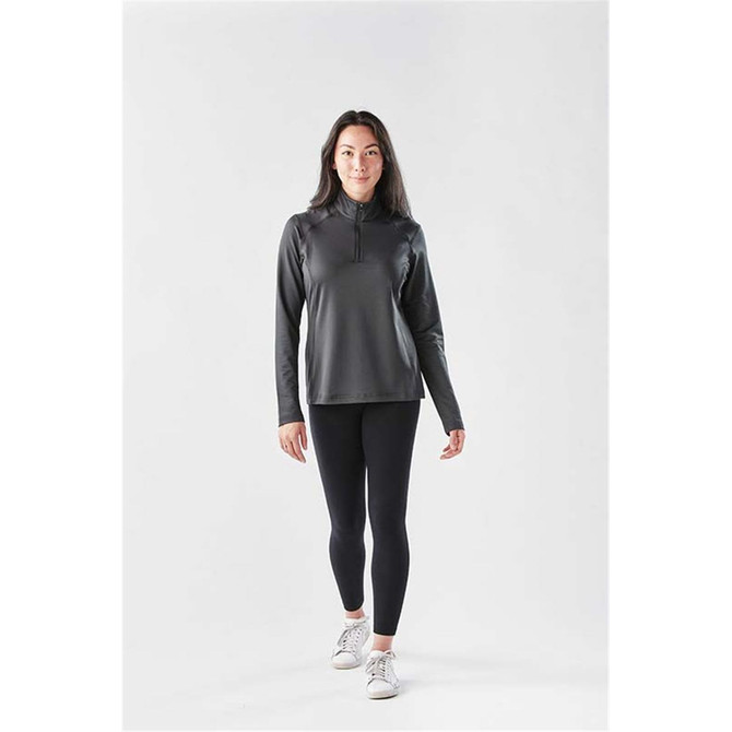 A long sleeve, quarter-zip jumper in dark grey, paired with black leggings and white sneakers, featuring a logo.
