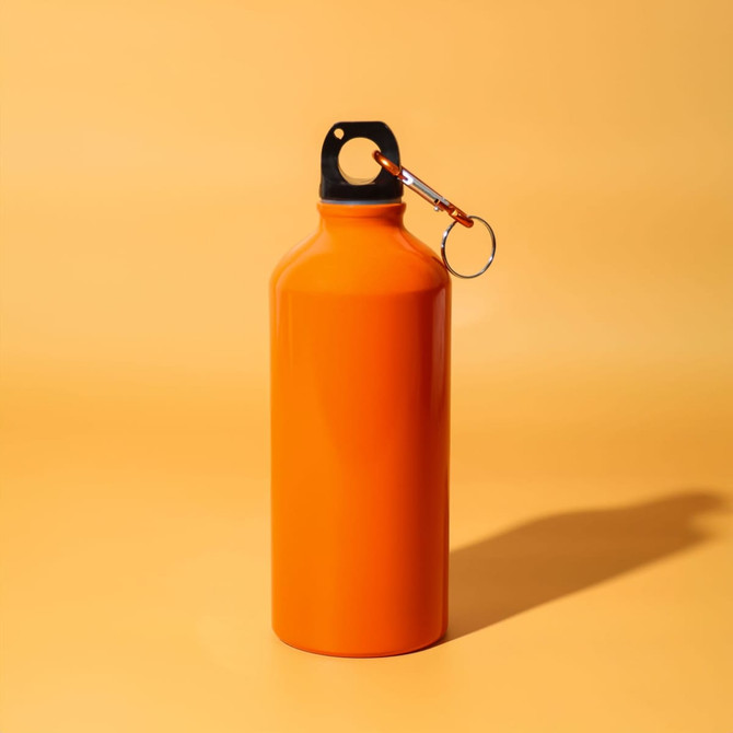 An orange drink bottle with a black cap and a silver keychain attachment against a yellow background.