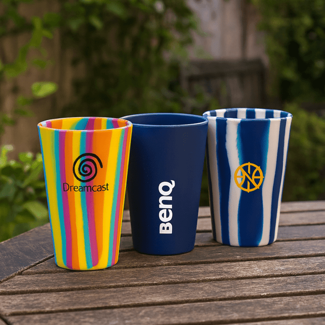 A drink cup set featuring a multicoloured striped cup, a navy blue cup with a logo, and a blue striped cup with a logo.