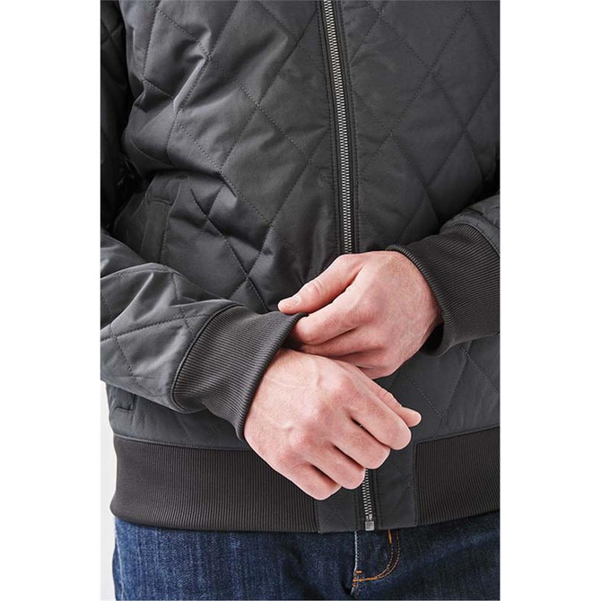 A grey quilted thermal jacket with a zip front and ribbed cuffs, featuring a logo on the chest.