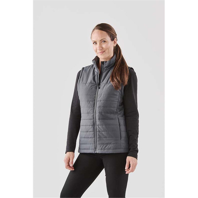 A woman in a grey 5-in-1 system jacket stands against a plain background, featuring a zippered front and stand-up collar.
