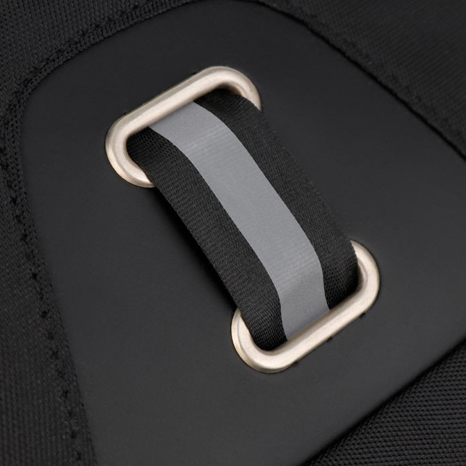 A close-up of a black backpack strap with a grey accent and a metal loop fastening. The backpack has a minimalist design.