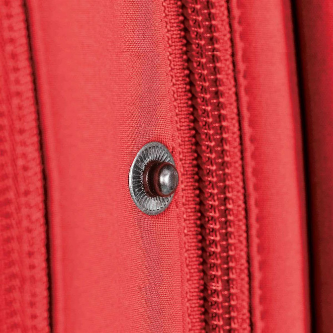 A close-up of a red fabric detail featuring a zipper and a decorative snap button, showcasing the material texture.