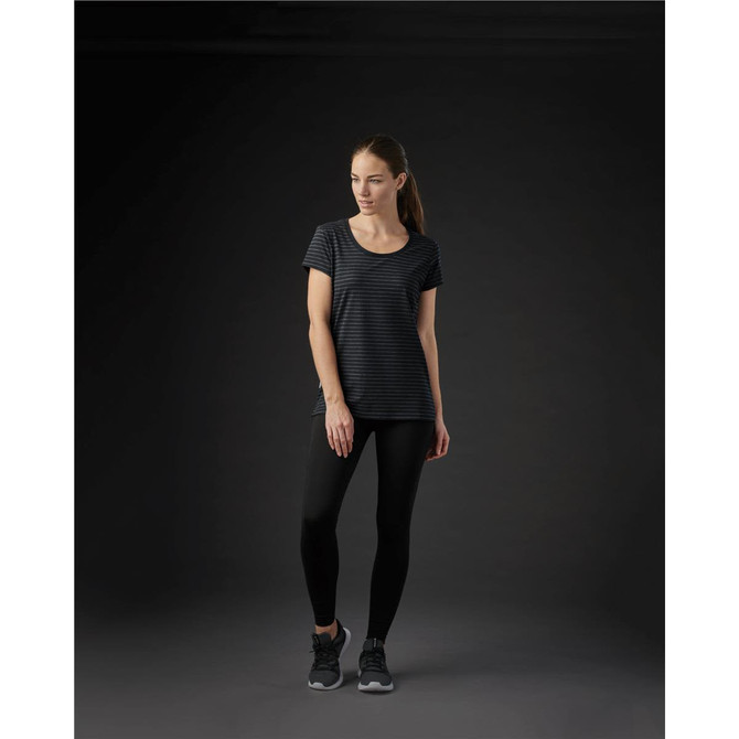 A women's crew neck tee in black with subtle stripes, paired with black leggings and sports shoes. The tee features a logo.