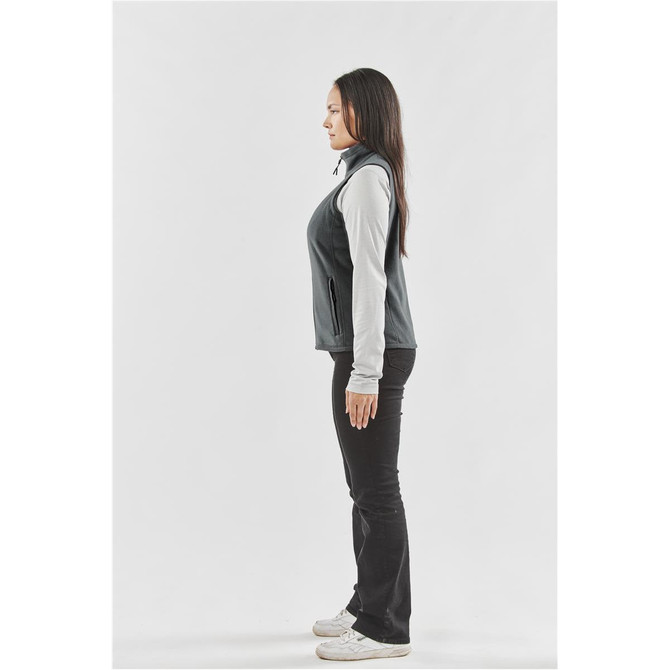 A women's fleece vest in dark grey, featuring a hood and side pockets, worn over a long-sleeve top.