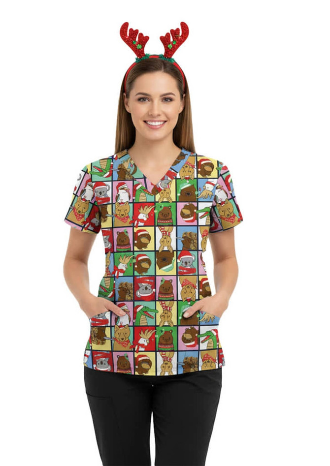 A women's Christmas scrub top featuring a colourful pattern with various festive cartoon animals, paired with reindeer antlers.