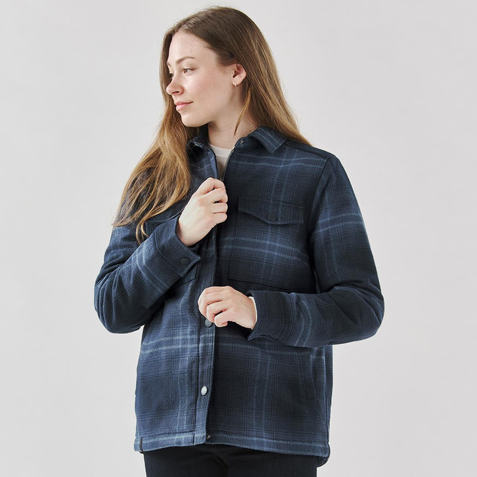 A woman wearing a navy plaid jacket with a Sherpa lining, featuring a button-up design and chest pocket.