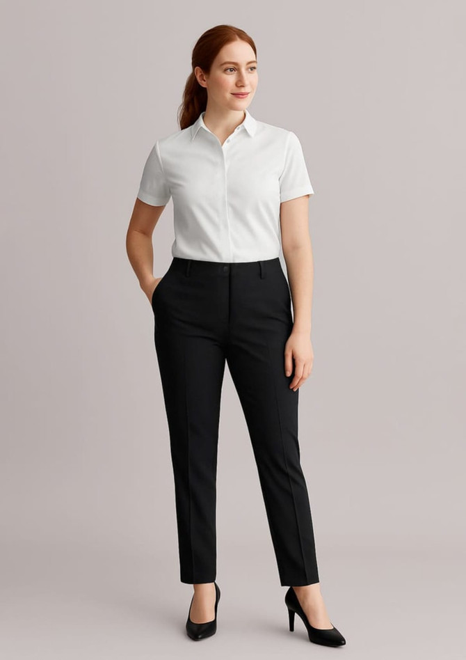 A woman stands wearing black bandless elastic waist pants and a white shirt, complemented by black heels.