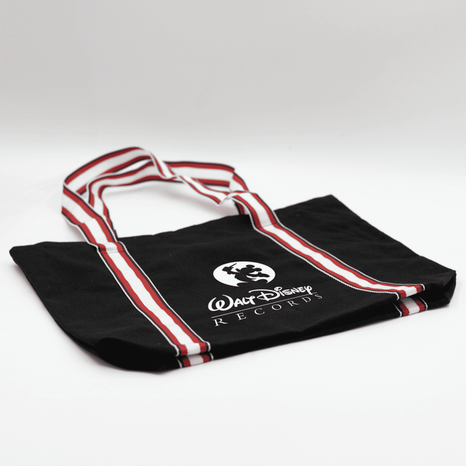A black canvas tote bag with red and white striped handles and a logo.