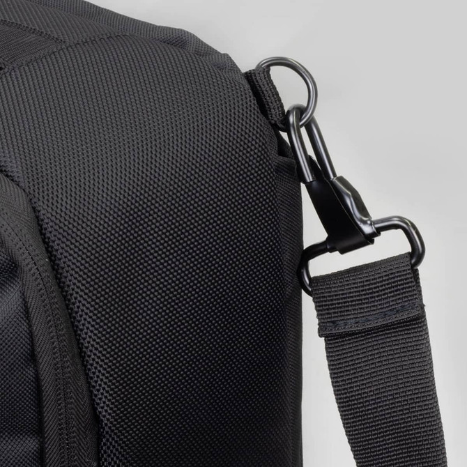 A black travel backpack with a textured surface, featuring a clip attachment and adjustable strap.