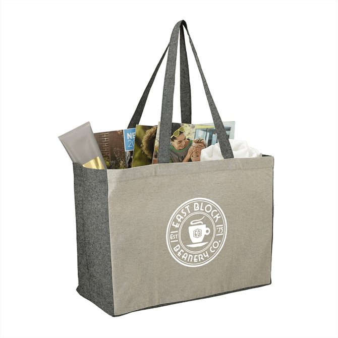 A grey recycled cotton tote bag with contrasting sides, featuring a logo and filled with magazines and a cosmetic product.
