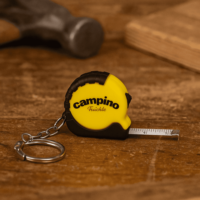A mini tape measure in yellow and black with a keychain attachment, resting on a wooden surface.
