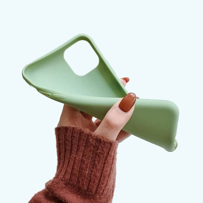 A green TPU iPhone case held in a hand, featuring a smooth texture and a cutout for the camera.