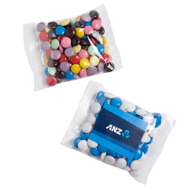 A package of colourful chocolate beans in various shades, including blue, pink, purple, white, and black, with a branding logo.