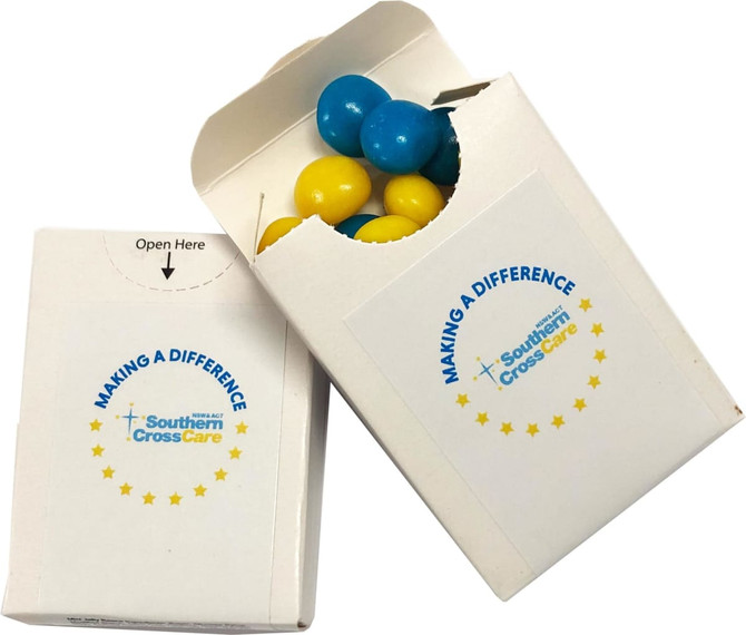 A white cardboard box with a blue and yellow chewy fruit inside, featuring a logo on the front.