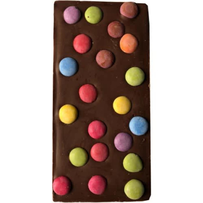 A chocolate bar with a smooth dark brown surface adorned with colourful, round candy spots in pink, blue, green, and yellow.