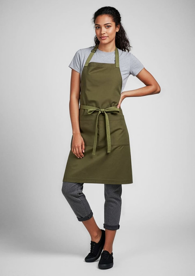 An olive green apron worn over a grey t-shirt, tied at the waist, paired with black pants and shoes.