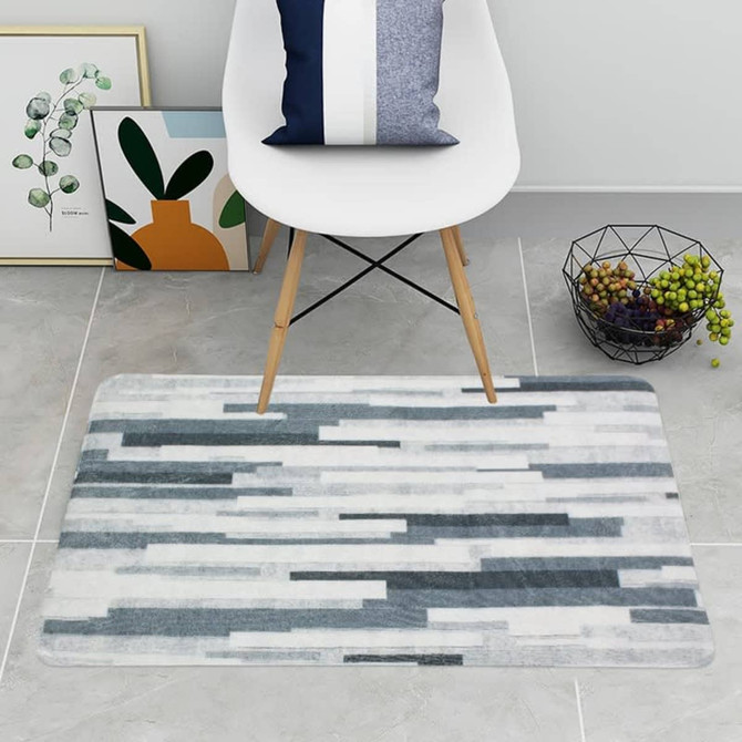A soft flannel logo mat featuring a pattern of grey and white stripes, placed on a tiled floor with a chair and decor.