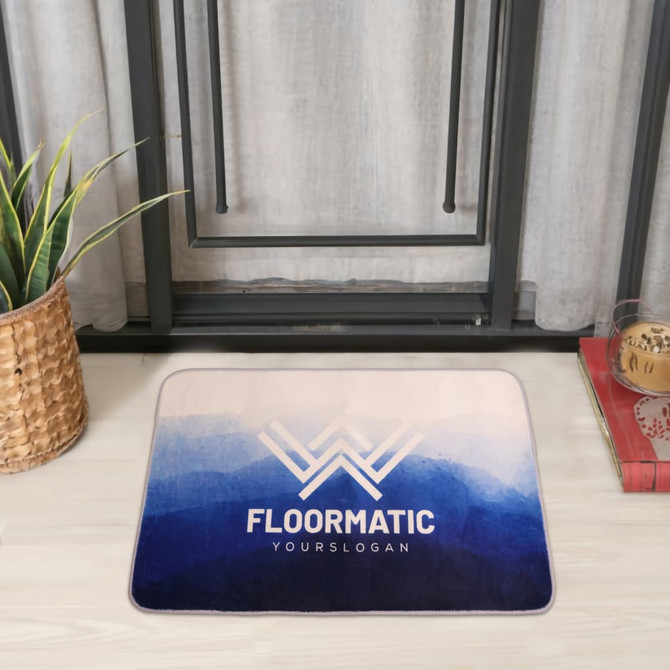 A flannel logo mat featuring a gradient of blue shades with a logo design. The mat lies on a light wooden floor.