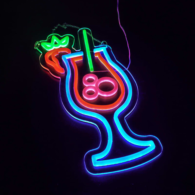 A neon LED sign featuring a colourful cocktail glass with a strawberry, glowing in green, blue, and pink.
