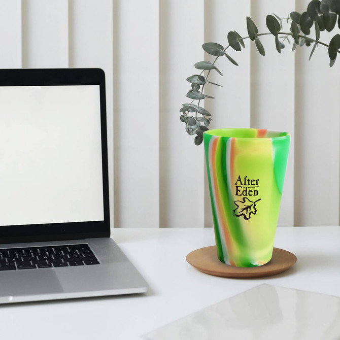 A green and yellow marbled silicone cup with a logo, placed beside a laptop on a desk.