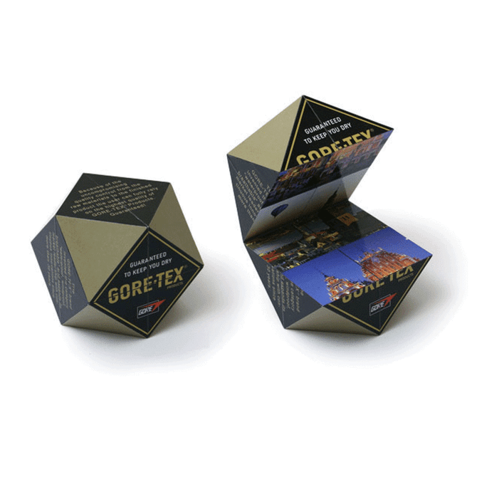 A diamond-shaped promotional cube in black and gold, featuring images on its faces and a logo.