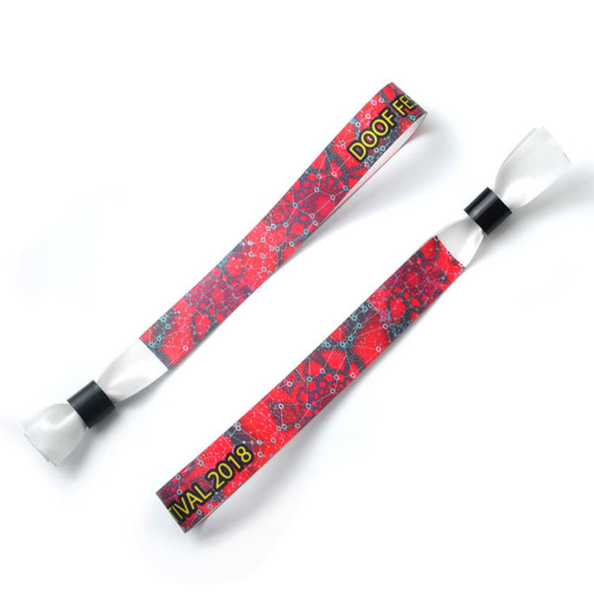 A red fabric wristband featuring a patterned design and with a black fastening. It includes a logo.