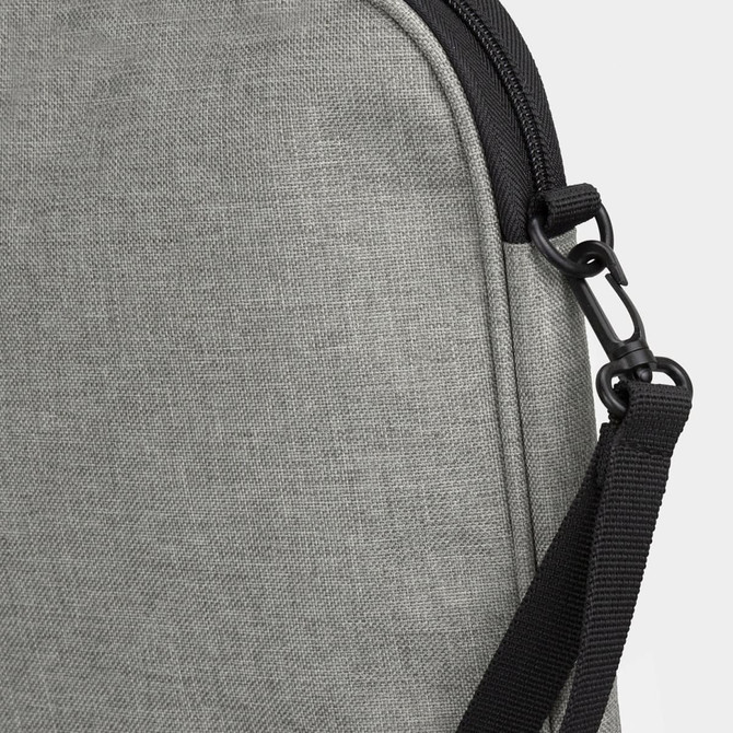 A grey satchel featuring a textured fabric and a black adjustable strap with a clip.