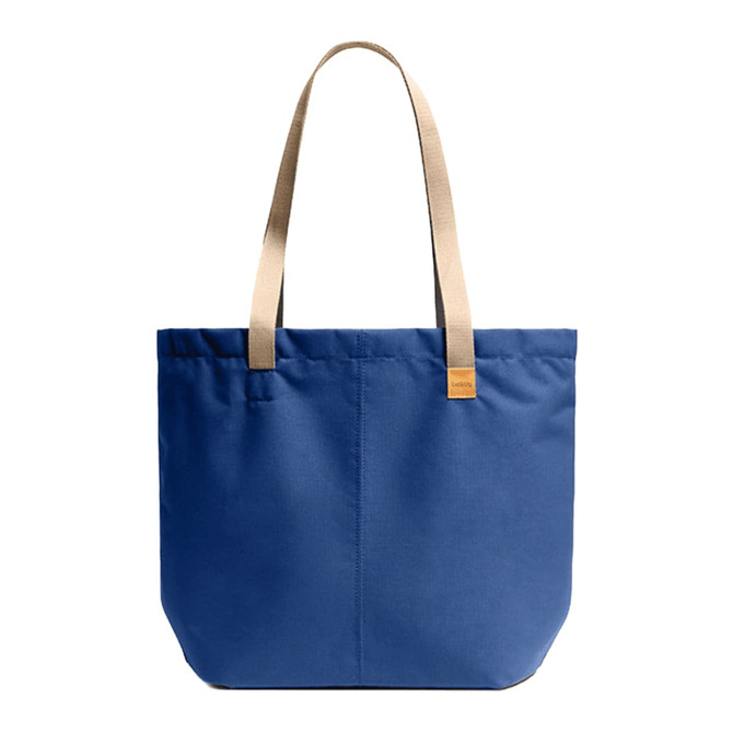 A blue tote bag with beige straps and a small logo. The bag features a simple, structured design.