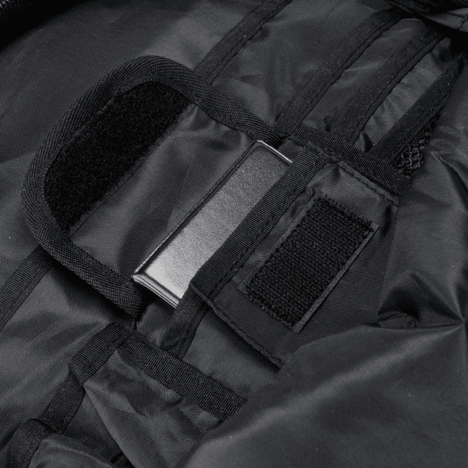 A close-up of a black backpack interior with fabric straps and a metal attachment point.