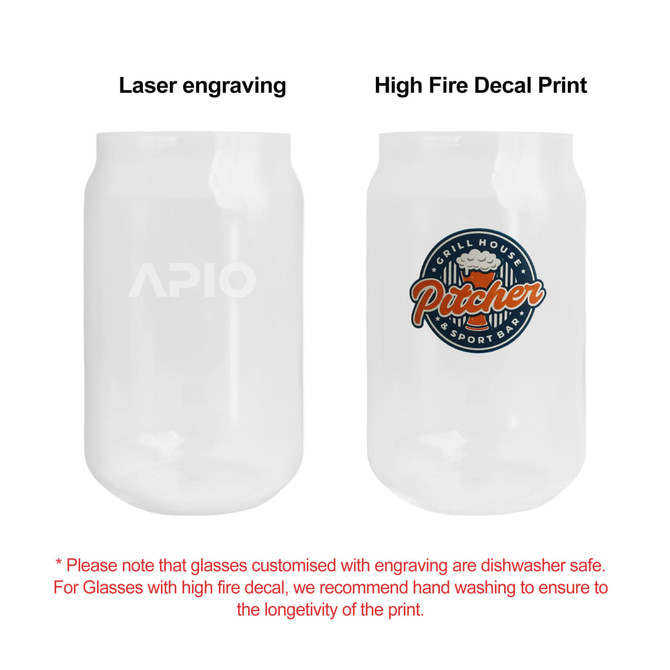 A can-shaped glass cup, featuring a logo on one side and a colourful decal on the other, both in clear glass.
