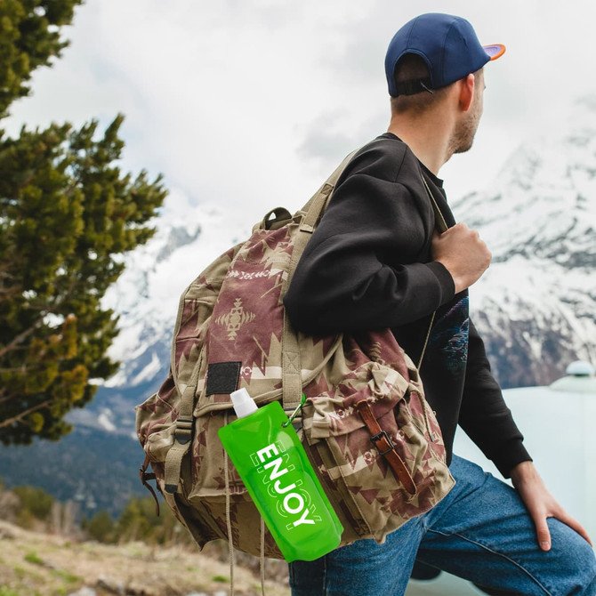 A drink bottle in a vibrant green colour attached to a backpack, set against a mountainous backdrop.