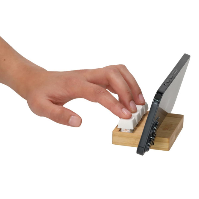 A bamboo stand keyboard stress reliever with a white keyboard and a smartphone on a wooden base.